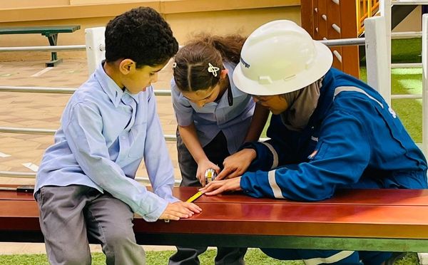 Young students at Abu Dhabi International School learning basic chores under the supervision of a parent