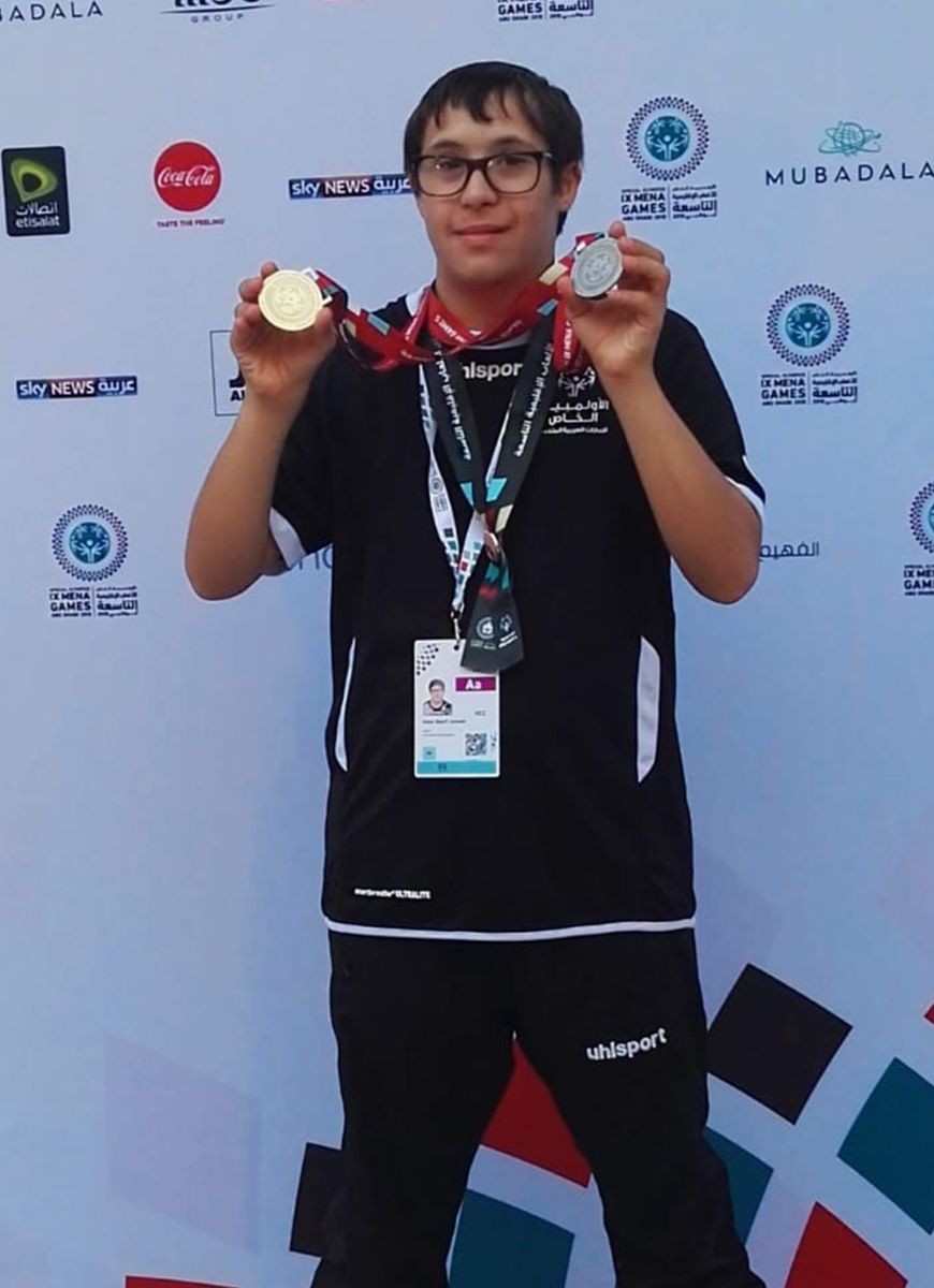 A special needs student at AIS displaying his winning sports medals